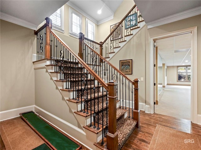 stairway featuring crown molding, recessed lighting, a towering ceiling, wood finished floors, and baseboards