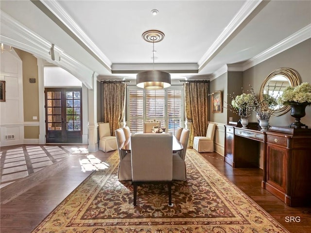 dining space featuring visible vents, arched walkways, a raised ceiling, dark wood-style flooring, and crown molding