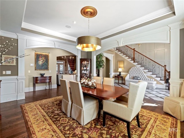 dining room featuring arched walkways, ornate columns, stairway, and a decorative wall