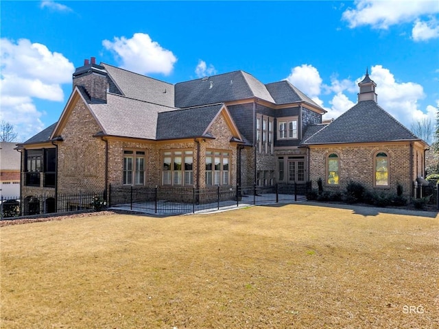 back of property with brick siding, a lawn, a chimney, and fence