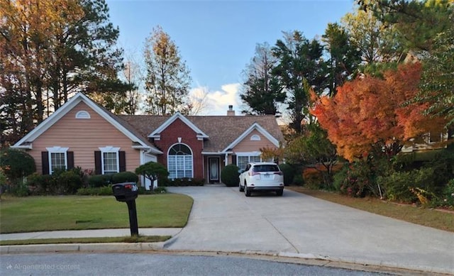 view of front facade featuring driveway, a chimney, and a front yard