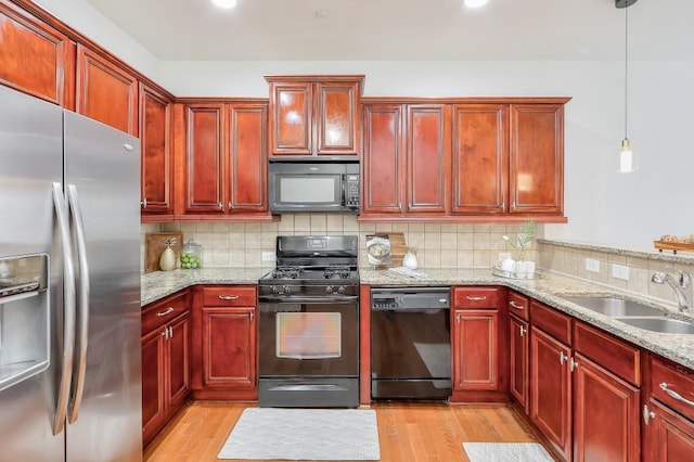 kitchen with reddish brown cabinets, light wood-style floors, a sink, and black appliances