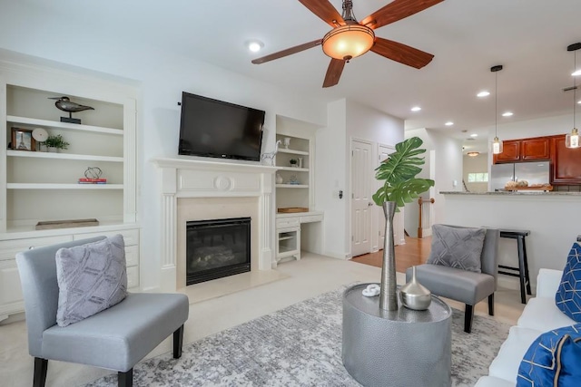 living area with built in features, recessed lighting, a fireplace, and a ceiling fan