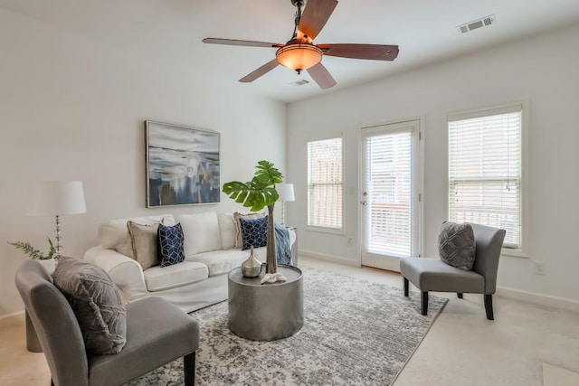 carpeted living area with baseboards, visible vents, and a ceiling fan