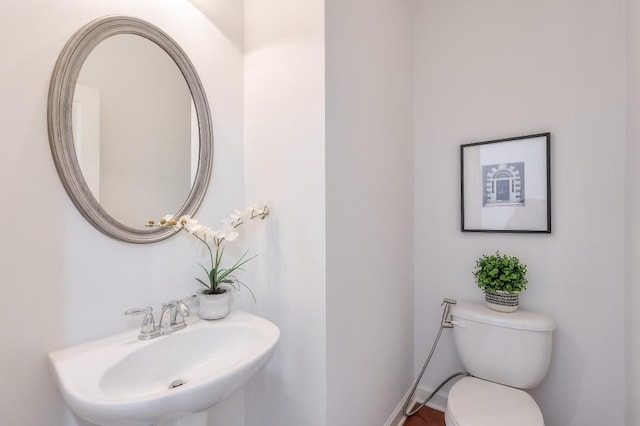 half bath featuring baseboards, a sink, and toilet