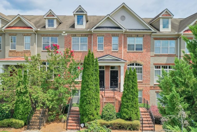 view of property featuring stairs and brick siding