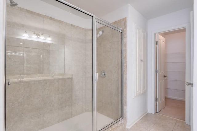 bathroom with a stall shower, a walk in closet, and tile patterned flooring