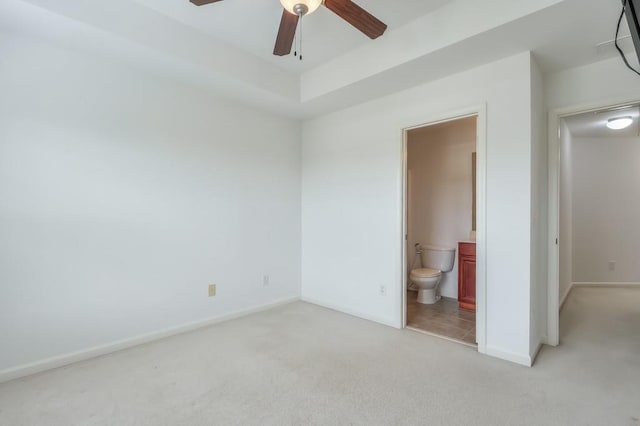 unfurnished bedroom with a ceiling fan, light colored carpet, baseboards, and ensuite bathroom