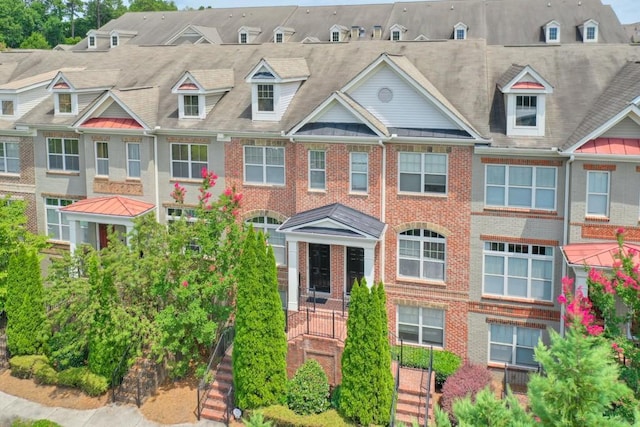 view of property with a standing seam roof, a residential view, and brick siding