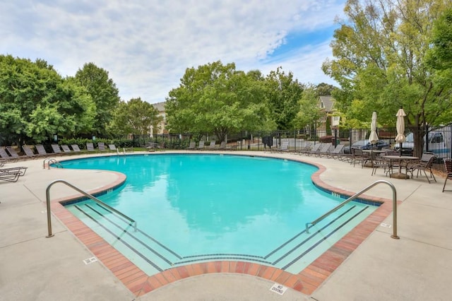 community pool with a patio area and fence