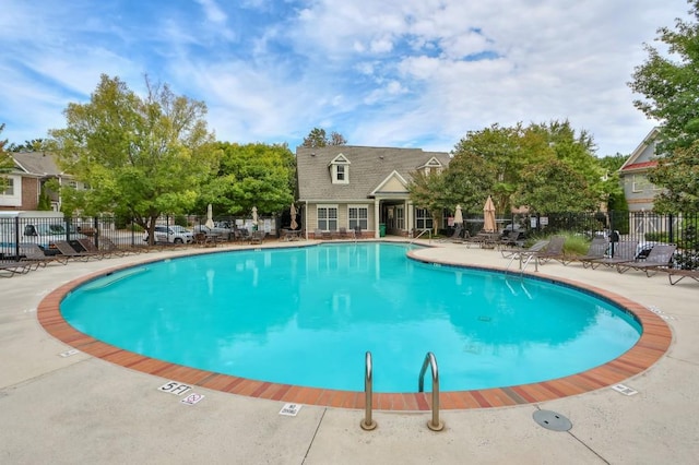 community pool with a patio area and fence