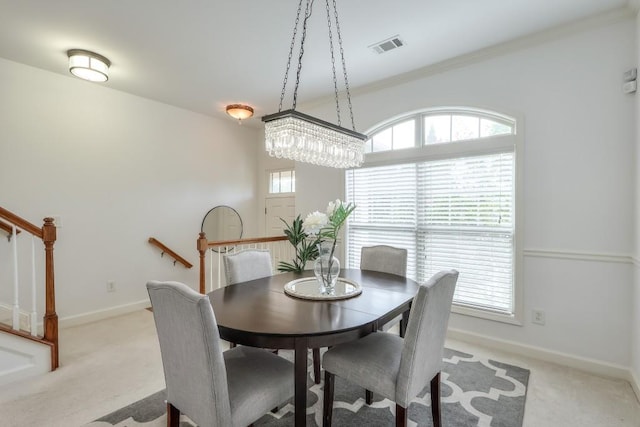 dining space featuring light carpet, visible vents, baseboards, stairs, and ornamental molding