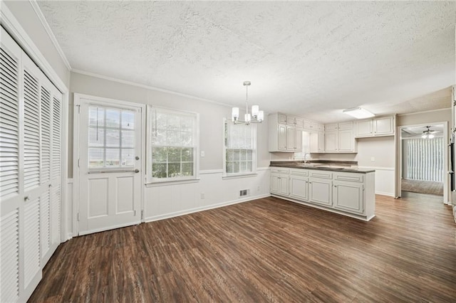 2466 Country Club Dr, Conyers, GA 30013 - kitchen featuring dark wood finished floors, a textured ceiling, a chandelier, dark countertops, and ornamental molding