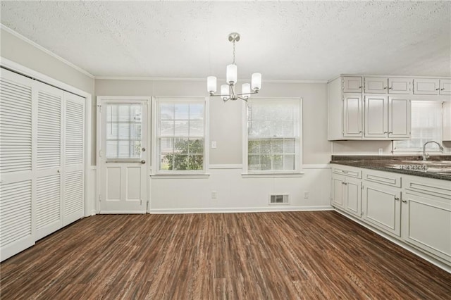 2466 Country Club Dr, Conyers, GA 30013 - unfurnished dining area featuring a textured ceiling, dark wood-style floors, a chandelier, a wainscoted wall, and crown molding