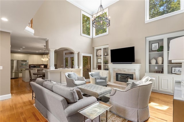 290 Edwardton Ct, Roswell, GA 30076 - living area with ornate columns, crown molding, a towering ceiling, light wood finished floors, and a fireplace
