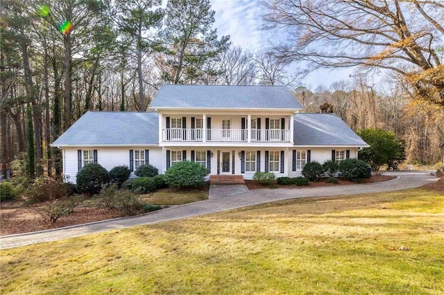 view of front of house featuring covered porch, a balcony, and a front lawn