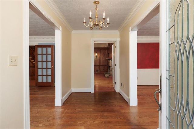 hallway with crown molding, a chandelier, a textured ceiling, and dark hardwood / wood-style floors