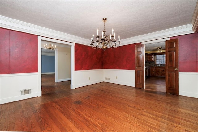 unfurnished room featuring a chandelier, crown molding, and dark hardwood / wood-style flooring