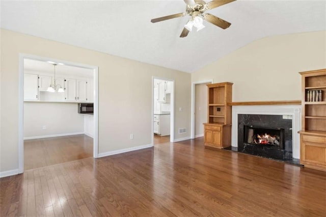 unfurnished living room with dark wood-type flooring, a fireplace, visible vents, baseboards, and vaulted ceiling