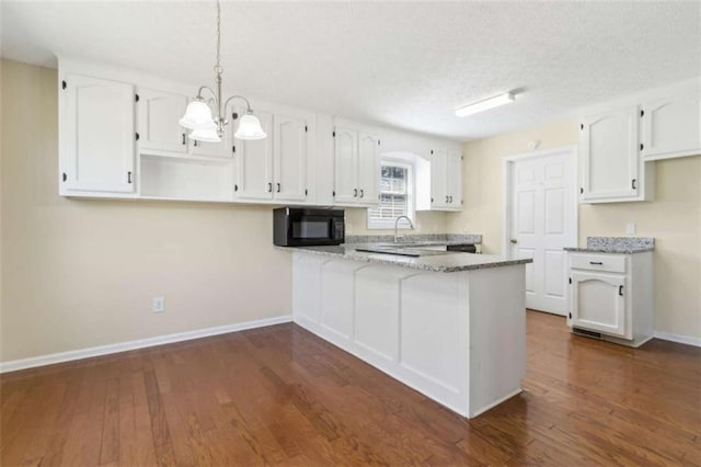 kitchen with baseboards, white cabinets, dark wood-type flooring, a peninsula, and black microwave