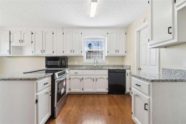 kitchen with wood-type flooring, white cabinets, a sink, light stone countertops, and black appliances