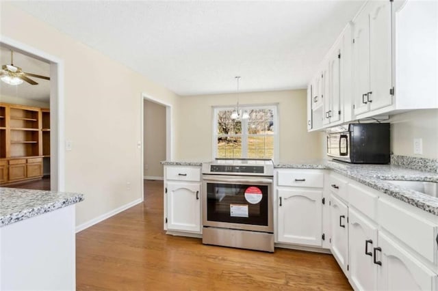 kitchen with a peninsula, stainless steel range with electric stovetop, black microwave, and white cabinets