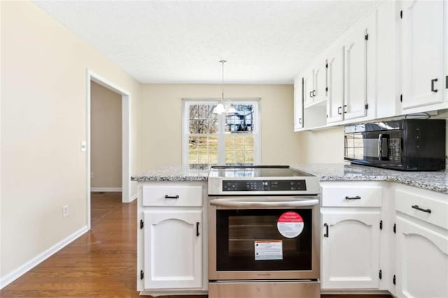 kitchen featuring black microwave, a peninsula, wood finished floors, white cabinets, and electric stove