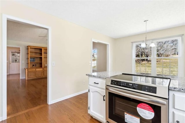 kitchen with light stone counters, light wood-style floors, baseboards, white cabinets, and stainless steel electric range oven