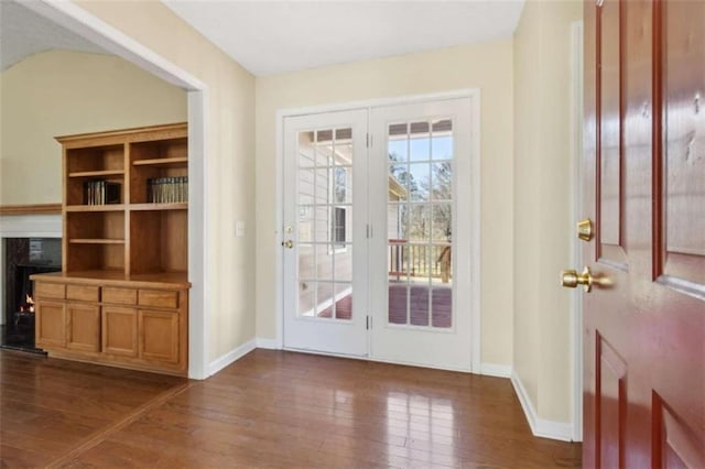 doorway to outside featuring wood-type flooring, a high end fireplace, and baseboards