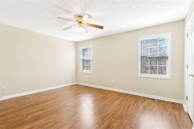 spare room featuring baseboards, a ceiling fan, a textured ceiling, and wood finished floors