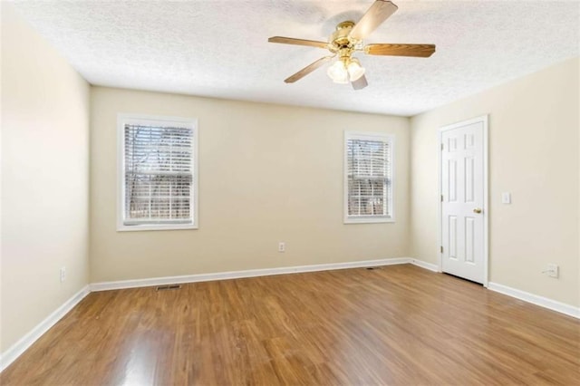 unfurnished room with a textured ceiling, plenty of natural light, and wood finished floors