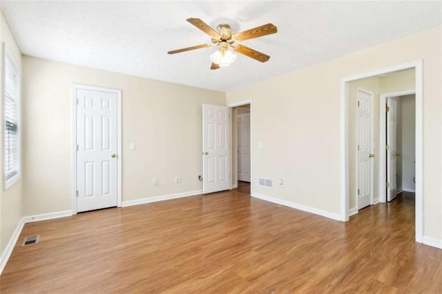 unfurnished bedroom with visible vents, ceiling fan, light wood-style flooring, and baseboards