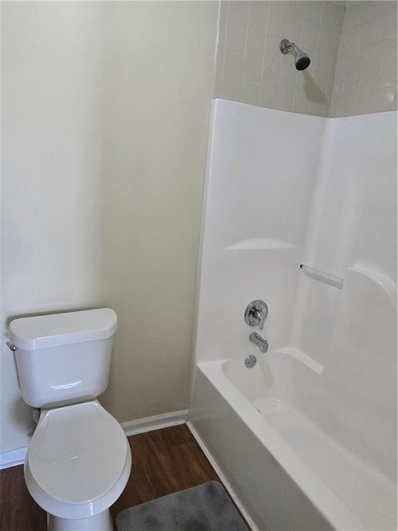 full bath with bathing tub / shower combination, wood finished floors, toilet, and baseboards