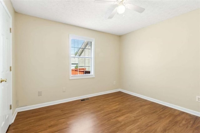 spare room featuring baseboards, visible vents, a ceiling fan, wood finished floors, and a textured ceiling