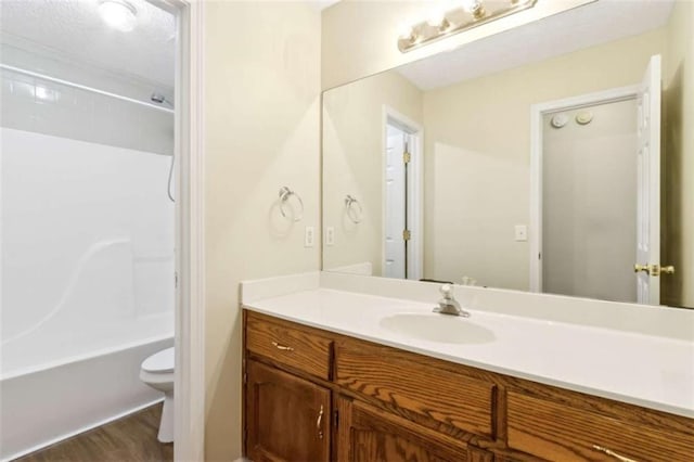 bathroom featuring toilet, bathing tub / shower combination, wood finished floors, and vanity