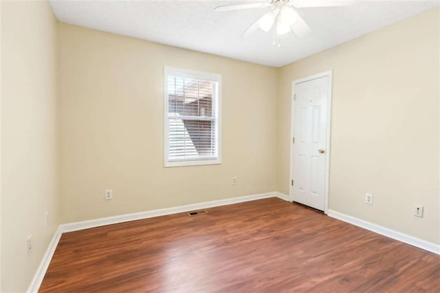 spare room with a ceiling fan, visible vents, baseboards, and wood finished floors