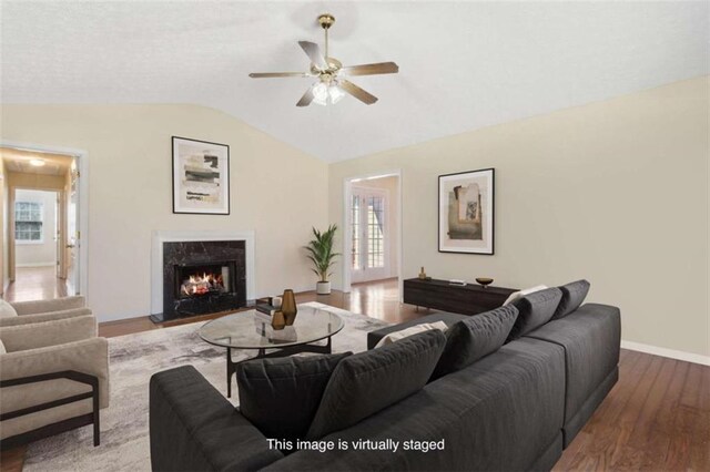 living room with baseboards, ceiling fan, a premium fireplace, wood finished floors, and vaulted ceiling