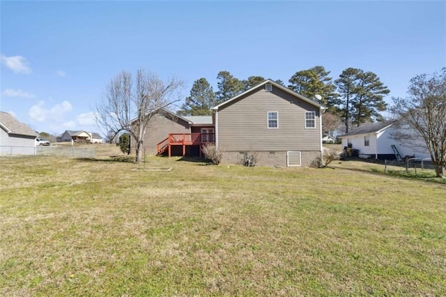 rear view of property with a wooden deck, fence, and a yard