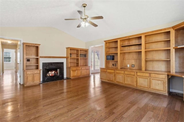 unfurnished living room featuring ceiling fan, a fireplace, vaulted ceiling, and dark wood-type flooring