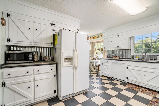 kitchen featuring a textured ceiling, sink, white appliances, and a wealth of natural light