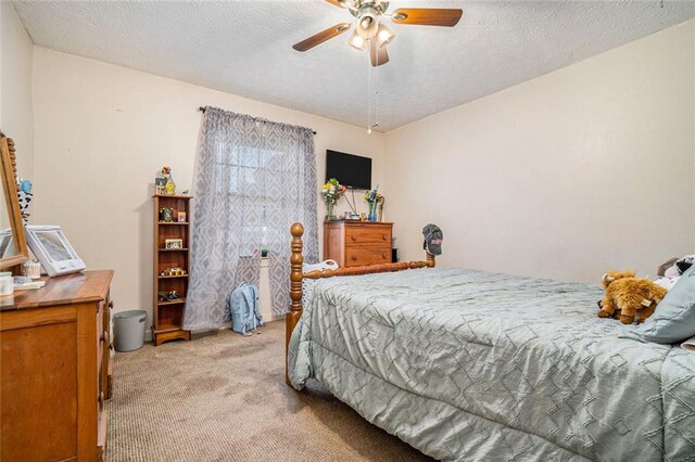 bedroom with ceiling fan, a textured ceiling, and light carpet