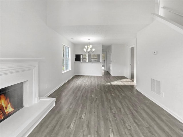 unfurnished living room featuring a notable chandelier and dark hardwood / wood-style floors