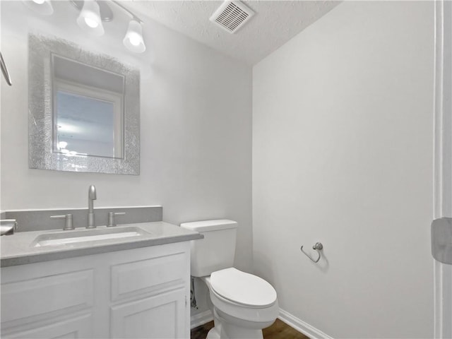 bathroom with vanity, toilet, and a textured ceiling