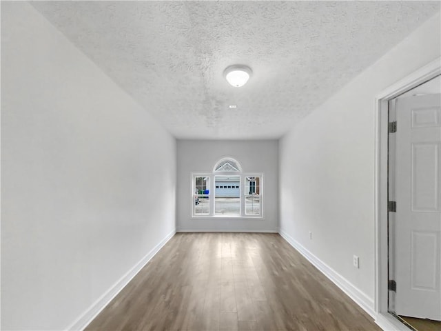 empty room with hardwood / wood-style flooring and a textured ceiling