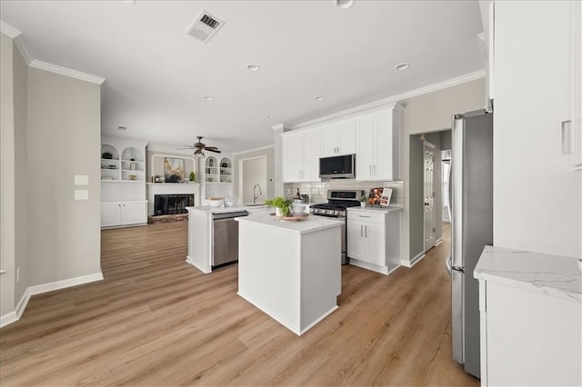 2870 Tattersall Ct, Cumming, GA 30041 - kitchen with stainless steel appliances, ceiling fan, open floor plan, crown molding, and white cabinetry