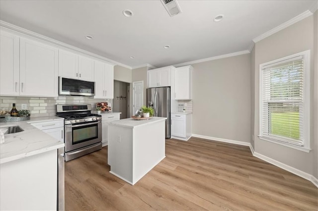 2870 Tattersall Ct, Cumming, GA 30041 - kitchen featuring stainless steel appliances, ornamental molding, backsplash, white cabinetry, and light wood-type flooring