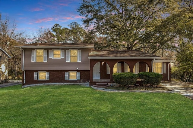 tri-level home featuring a front lawn and brick siding