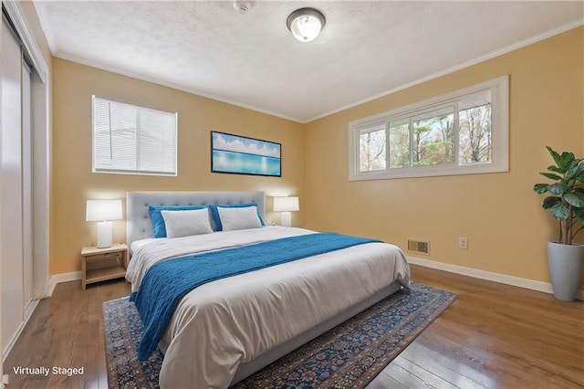 bedroom featuring crown molding, wood finished floors, and baseboards