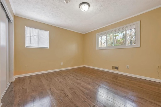 unfurnished room with visible vents, ornamental molding, baseboards, and hardwood / wood-style floors