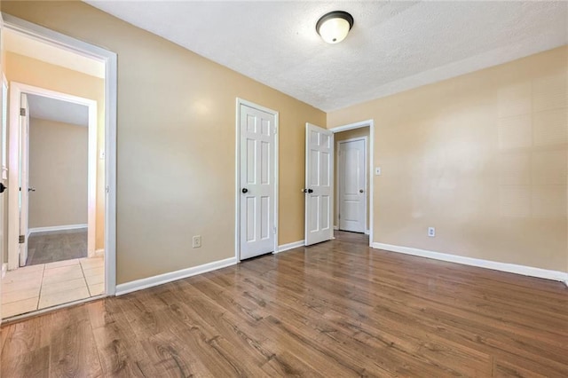 unfurnished bedroom with wood finished floors, baseboards, and a textured ceiling